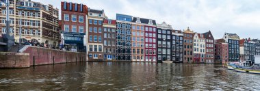 AMSTERDAM, HOLLLAND - 18 Nisan 2023: Hollanda 'nın başkentinde sanatsal mirası, ayrıntılı kanal sistemi ve dar cepheli evleri ile tanınan tipik Hollandalı evler