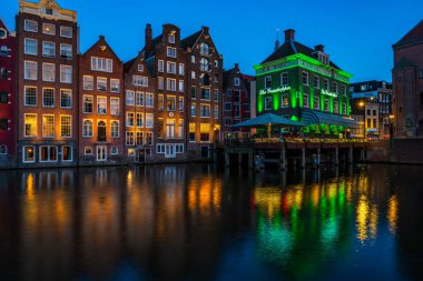 AMSTERDAM, HOLLAND - 18 Nisan 2023: Hollanda başkentinde sanatsal mirası, ayrıntılı kanal sistemi ve dar cepheli evleri ile bilinen bir kanal hattı