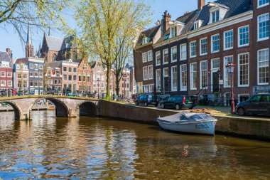 AMSTERDAM, HOLLLAND - 17 Nisan 2023: Amsterdam, Hollanda 'da özenle hazırlanmış kanal sistemi, dar evleri ve şehir çevresinde sayısız bisiklet yolu bulunan bisiklet yollarıyla bilinen bir kanal manzarası