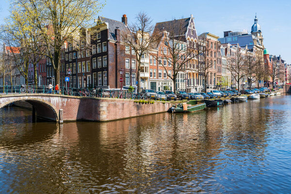 AMSTERDAM, HOLLAND - APRIL 17, 2023: View of a canal in Amsterdam, Netherlands capital known for its elaborate canal system, narrow houses and cycling with numerous bike paths around the city