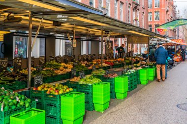 AMSTERDAM, HOLLAND - 18 Nisan 2023: Müşteriler Amsterdam Katestraat yerel sokak gıda pazarından taze ürün satın alıyorlar.