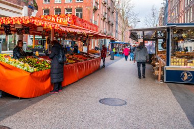 AMSTERDAM, HOLLAND - 18 Nisan 2023: Müşteriler Amsterdam Katestraat yerel sokak gıda pazarından taze ürün satın alıyorlar.