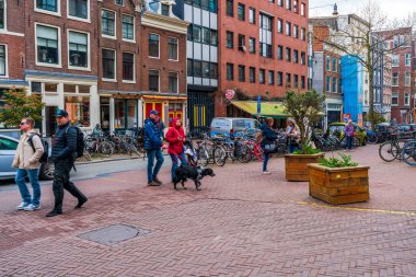 AMSTERDAM, HOLLLAND - 17 Nisan 2023: Amsterdam sokak manzarası, ayrıntılı kanal sistemi, dar evler ve şehir çevresinde sayısız bisiklet yolu ile bilinen canlı Hollanda başkenti
