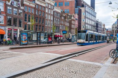 AMSTERDAM, HOLLLAND - 17 Nisan 2023: Amsterdam sokak manzarası, ayrıntılı kanal sistemi, dar evler ve şehir çevresinde sayısız bisiklet yolu ile bilinen canlı Hollanda başkenti