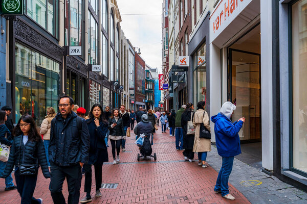 AMSTERDAM, HOLLAND - APRIL 18, 2023: Shoppers on Kalverstraat street, Amsterdam's busiest shopping street which runs from Dam Square to Muntplein square