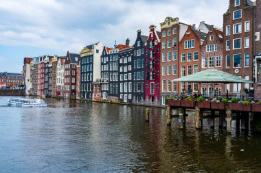 AMSTERDAM, HOLLAND - 18 Nisan 2023: Hollanda başkentinde sanatsal mirası, ayrıntılı kanal sistemi ve dar cepheli evleri ile bilinen bir kanal hattı