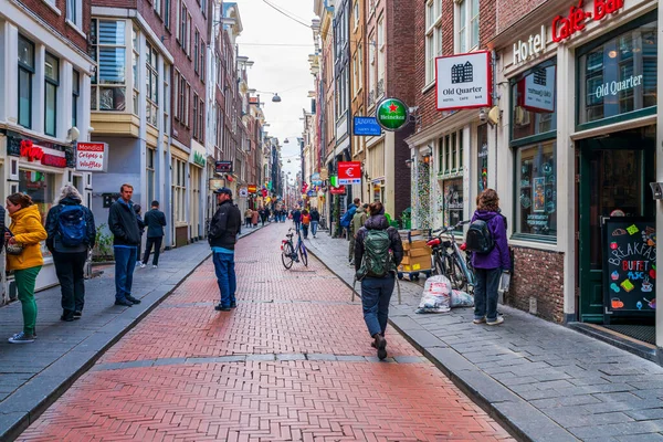 AMSTERDAM, HOLLLAND - 18 Nisan 2023: Amsterdam 'ın en eski caddelerinden biri olan Warmoesstraat Caddesi' ndeki Alışverişçiler, Nieuwebrugsteeg 'den Dam Meydanı' na kadar Damrak 'a paralel ilerliyor..