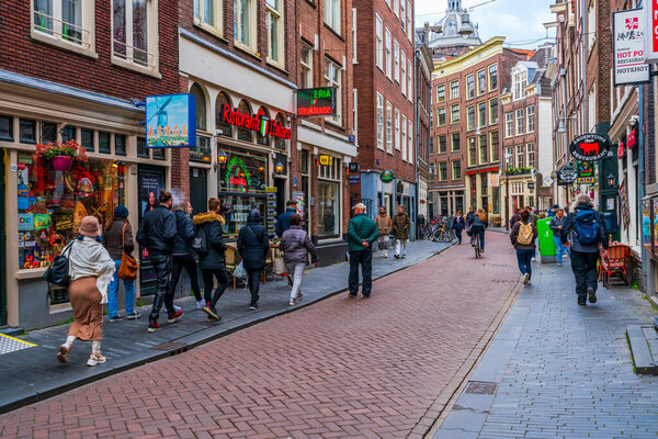 AMSTERDAM, HOLLAND - APRIL 18, 2023: Shoppers on Warmoesstraat street, one of the oldest streets in Amsterdam, running parallel to Damrak from Nieuwebrugsteeg to Dam Square.