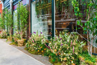 LONDON, İngiltere - 24 Mayıs 2023: Londra 'daki Bloom yıllık çiçek sergisi sırasında Chelsea' de bir mağazanın vitrinini muhteşem bir çiçek sergisi dekore etti