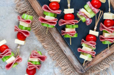 Salamlı, peynirli, kiraz domatesli ve salatalıklı mini Yunan şarküteri kebabı.