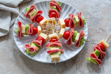 Salamlı, peynirli, kiraz domatesli ve salatalıklı mini Yunan şarküteri kebabı.