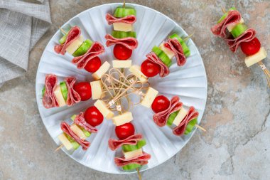 Salamlı, peynirli, kiraz domatesli ve salatalıklı mini Yunan şarküteri kebabı.