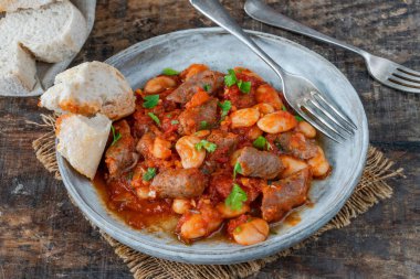 Beef chipolatas and bean casserole with crusty bread clipart