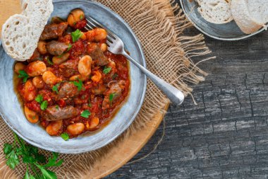 Beef chipolatas and bean casserole with crusty bread clipart