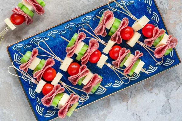 Salamlı, peynirli, kiraz domatesli ve salatalıklı mini Yunan şarküteri kebabı.
