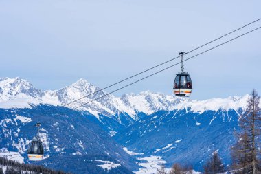 KRONPLATZ, ITALY - 21 Ocak 2024: Kablolu araçlar kayakçıları ve snowboardcuları İtalya 'da popüler bir kış sporları merkezi olan Kronplatz' daki dağın tepesine çıkarıyor.