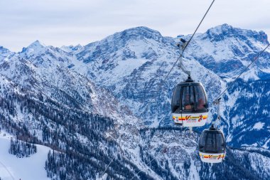 KRONPLATZ, ITALY - 21 Ocak 2024: Kablolu araçlar, İtalya 'da popüler bir kış sporları merkezi olan Kronplatz' daki bir dağın tepesine kayakçıları ve snowboardcuları çıkarıyor.
