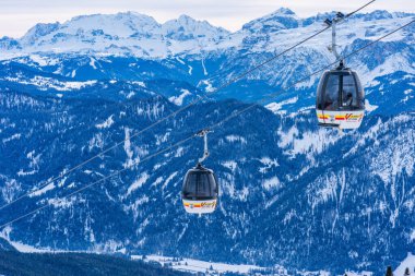 KRONPLATZ, ITALY - 21 Ocak 2024: Kablolu araçlar, İtalya 'da popüler bir kış sporları merkezi olan Kronplatz' daki bir dağın tepesine kayakçıları ve snowboardcuları çıkarıyor.