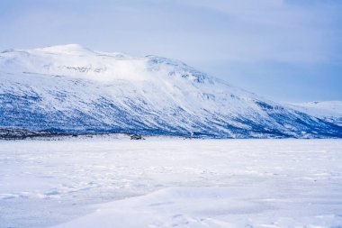 Frozen lake Tornetrask and snow covered mountains around Abisko, Sweden clipart