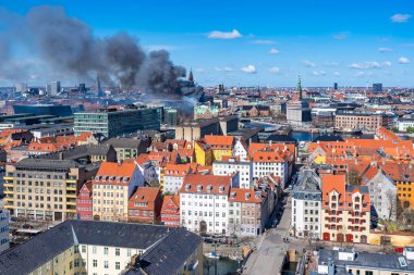 COPENHAGEN, DENMARK - APRIL 16, 2024: Black smoke drifts over central Copenhagen as historic Copenhagen Stock Exchange goes up in flames on Tuesday morning. clipart