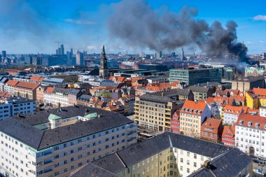 COPENHAGEN, DENMARK - APRIL 16, 2024: Black smoke drifts over central Copenhagen as historic Copenhagen Stock Exchange goes up in flames on Tuesday morning. clipart