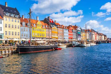 COPENHAGEN, DENMARK - 14 Nisan 2024: Kopenhag 'da Nyhavn seti, Danimarka' nın başkentindeki en popüler turizm merkezlerinden biri olan eski ev, kafe ve restoranların renkli cepheleriyle kaplıdır..