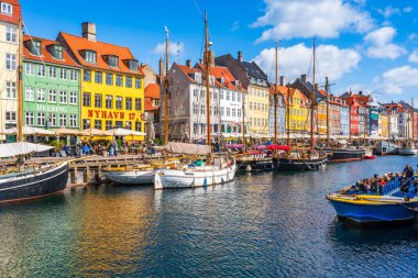 COPENHAGEN, DENMARK - 14 Nisan 2024: Kopenhag 'da Nyhavn seti, Danimarka' nın başkentindeki en popüler turizm merkezlerinden biri olan eski ev, kafe ve restoranların renkli cepheleriyle kaplıdır..