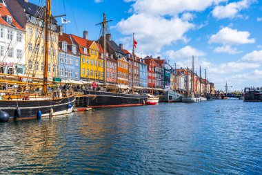 COPENHAGEN, DENMARK - 14 Nisan 2024: Kopenhag 'da Nyhavn seti, Danimarka' nın başkentindeki en popüler turizm merkezlerinden biri olan eski ev, kafe ve restoranların renkli cepheleriyle kaplıdır..