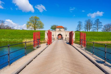 COPENHAGEN, DENMARK - 17 Nisan 2024: Danimarka 'nın Kopenhag kentindeki Kastellet Kalesi' nin güney girişine giden hendeğin üzerinden geçen ziyaretçiler