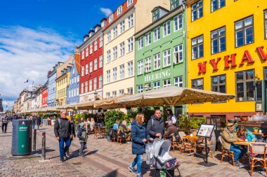 COPENHAGEN, DENMARK - 17 Nisan 2024: Kopenhag 'daki Nyhavn seti, Danimarka' nın başkentindeki en popüler turizm merkezlerinden biri olan eski ev, kafe ve restoranların renkli cepheleriyle kaplıdır..