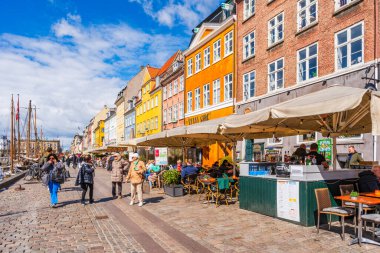 COPENHAGEN, DENMARK - 17 Nisan 2024: Kopenhag 'daki Nyhavn seti, Danimarka' nın başkentindeki en popüler turizm merkezlerinden biri olan eski ev, kafe ve restoranların renkli cepheleriyle kaplıdır..