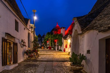 ALBEROBELLO, İtalya - 16 Mayıs 2024: Alberobello 'da konik çatıları olan ünlü eski kuru taş trulli evleri görmek. Alberobello 'nun tarihi merkezi UNESCO tarafından dünya mirası olarak ilan edildi..