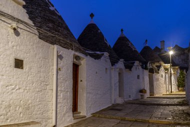 İtalya 'nın Alberobello şehrinde konik çatıları olan ünlü tarihi kuru taş trulli evler. Gece görünümü