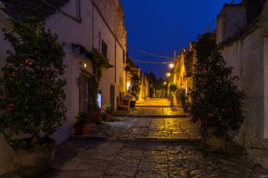 İtalya 'nın Alberobello şehrinde konik çatıları olan ünlü tarihi kuru taş trulli evler. Gece görünümü