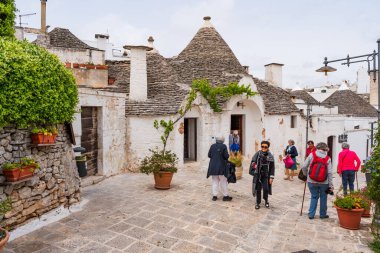 ALBEROBELLO, İtalya - 16 Mayıs 2024: İtalya 'nın Puglia bölgesindeki küçük bir İtalyan kasabası olan Alberobello' da turist gezisi. Alberobello 'nun tarihi merkezi UNESCO tarafından dünya mirası olarak ilan edildi.