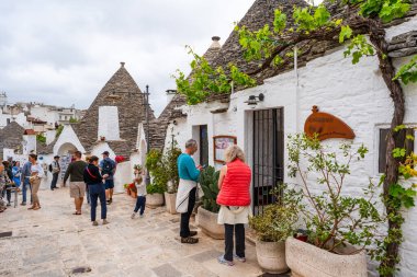 ALBEROBELLO, İtalya - 16 Mayıs 2024: İtalya 'nın Puglia bölgesindeki küçük bir İtalyan kasabası olan Alberobello' da turist gezisi. Alberobello 'nun tarihi merkezi UNESCO tarafından dünya mirası olarak ilan edildi.