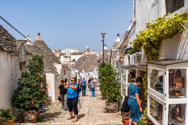 ALBEROBELLO, İtalya - 16 Mayıs 2024: İtalya 'nın Puglia bölgesindeki küçük bir İtalyan kasabası olan Alberobello' da turist gezisi. Alberobello 'nun tarihi merkezi UNESCO tarafından dünya mirası olarak ilan edildi.