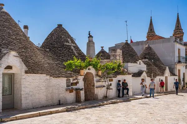 stock image ALBEROBELLO, ITALY - MAY 17, 2024: Tourists sightseeing in Alberobello, a small Italian town in Italian region of Puglia. Historical centre of Alberobello was declared by UNESCO as World heritage site