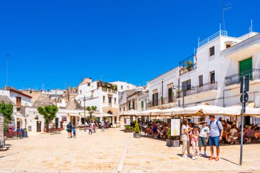 ALBEROBELLO, İtalya - 17 Mayıs 2024: İtalya 'nın Puglia bölgesindeki küçük bir İtalyan kasabası olan Alberobello' da turist gezisi. Alberobello 'nun tarihi merkezi UNESCO tarafından dünya mirası olarak ilan edildi.