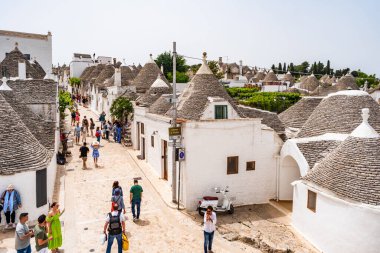 ALBEROBELLO, İtalya - 18 Mayıs 2024: İtalya 'nın Puglia bölgesindeki küçük bir İtalyan kasabası olan Alberobello' da turist gezisi. Alberobello 'nun tarihi merkezi UNESCO tarafından dünya mirası olarak ilan edildi.