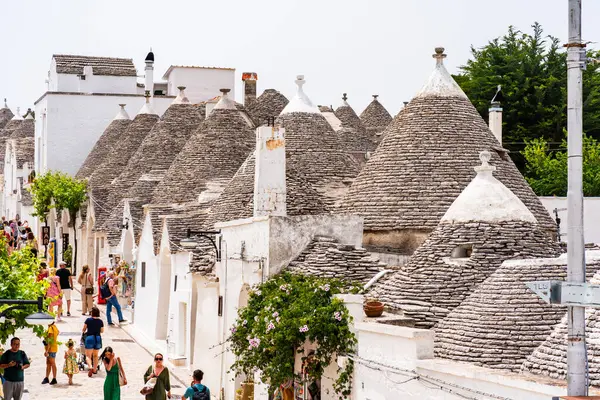 stock image ALBEROBELLO, ITALY - MAY 18, 2024: Tourists sightseeing in Alberobello, a small Italian town in Italian region of Puglia. Historical centre of Alberobello was declared by UNESCO as World heritage site