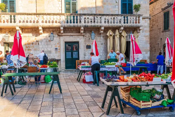 stock image DUBROVNIK, CROATIA - JUNE 29, 2024: People shop at Gunduliceva Poljana open-air market in Dubrovnik Old City which has many stalls full of seasonal fruit and vegetables as well as other local products