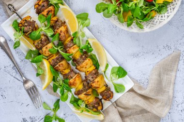 Izgara kuzu, sarı biber ve yeşil yaprak salatalı bebek patates şişleri.