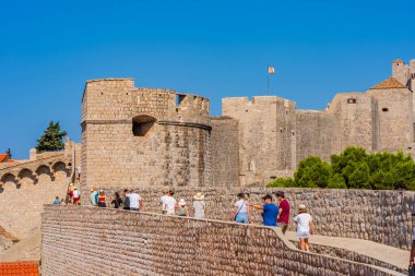 DUBROVNIK, CROATIA - 29 Haziran 2024: Turistler Dubrovnik 'in ünlü ve popüler bir turizm beldesi olan tarihi Eski Şehir' i çevreleyen görkemli antik şehir duvarlarında yürüyorlar.