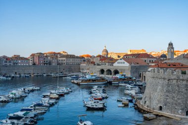 DUBROVNIK, CROATIA - 29 Haziran 2024: Ortaçağ simgeleriyle Dubrovnik Eski Limanı manzarası. Yüzlerce yıllık iskele duvarları ve kompakt bir limanın etrafını gözetleyenler lüks restoran teraslarıyla çevrili..