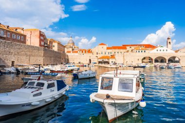 DUBROVNIK, CROATIA - 27 Haziran 2024: Ortaçağ simgeleriyle Eski Dubrovnik Limanı manzarası. Yüzlerce yıllık iskele duvarları ve kompakt bir limanın etrafını gözetleyenler lüks restoran teraslarıyla çevrili..