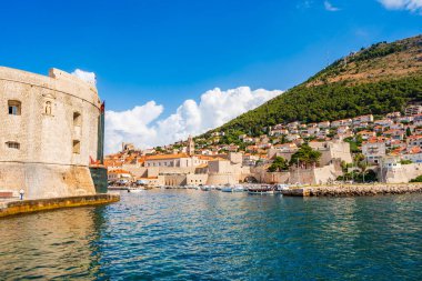 DUBROVNIK, CROATIA - 27 Haziran 2024: Ortaçağ simgeleriyle Eski Dubrovnik Limanı manzarası. Yüzlerce yıllık iskele duvarları ve kompakt bir limanın etrafını gözetleyenler lüks restoran teraslarıyla çevrili..