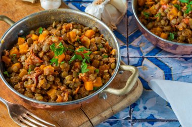 Kahverengi mercimek yahnisi, beyaz şarap, serrano jambonu ve füme paprika.