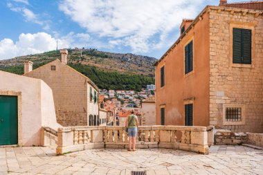 DUBROVNIK, CROATIA - 27 Haziran 2024: Turist Boscovich Meydanı 'nın tepesinden Dubrovnik' in tarihi Eski Kent manzarasına hayran.