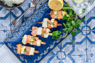 Mini somon ve halibut şişleri bal, biberiye ve limonla marine edilmiş.